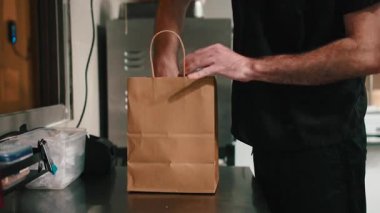 Tanınmayan bir aşçı paket servis için yemek ve fiş alıyor.