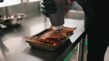 Profesyonel şef restoranda ızgara domuz pirzolası ve barbekü sosu hazırlıyor.