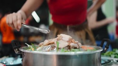 Geleneksel Tayland usulü barbekü güvecinde ızgara domuz eti pişiren birini yakından çek.