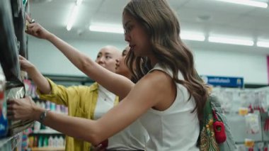 Bir grup mutlu Asyalı genç bayan arkadaş marketin koridorunda alışveriş yapıyorlar.