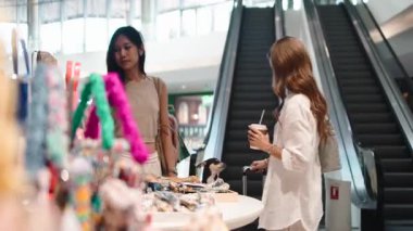 İki genç kadın ve küçük bir köpek modern bir alışveriş merkezinde birlikte alışveriş yapıyorlar.