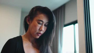 Güzel orta yaşlı Taylandlı kadın yüz kremi sürüyor ve saçını aynanın önünde şekillendiriyor.