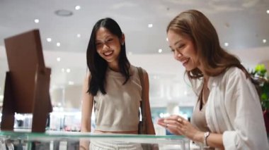 İki mutlu arkadaş alışveriş merkezindeki lüks bir mağazada birlikte mücevher seçip alıyorlar.