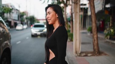 Uzun saçlı güzel atletik kadın yoğun bir şehir caddesinde rahatça yürüyor.