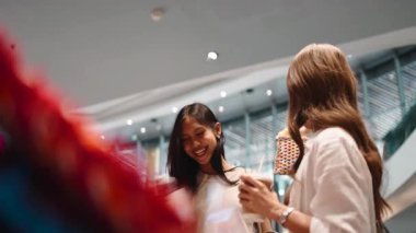 İki neşeli bayan arkadaş alışveriş yapıp kahve içerek eğleniyorlar.