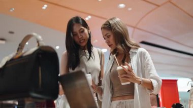 İki bayan arkadaş lüks bir perakende mağazasında ürün alırken keyif çatıp sohbet ediyorlar.