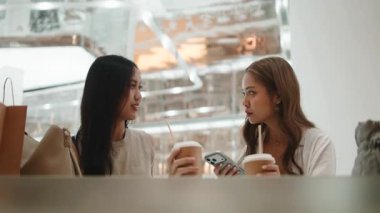 Güzel bayan arkadaşlar kahveden zevk alıyorlar, hikayelerini paylaşıyorlar ve akıllı telefon kullanarak gülüyorlar.