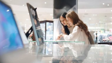 Modern bir perakende ortamda gezinen ve öğeleri seçen iki arkadaş