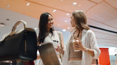 Modern bir mağazada alışveriş yapan mutlu Taylandlı kadınlar, dostça sohbet ve yaşam tarzı anlarını paylaşıyorlar.