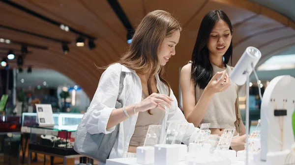 Genç Asyalı kadın çift perakende terapiden zevk alıyor, bir butikte güzel mücevherler seçiyorlar.