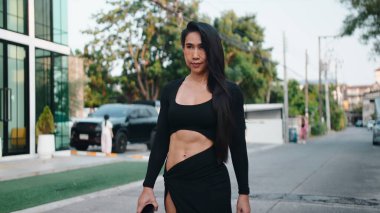 Empowered thai woman with strong physique walking city street during lifestyle moment