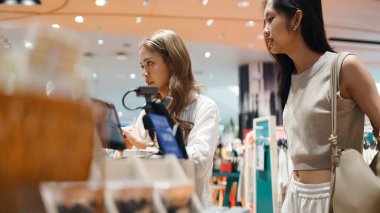 İki genç Taylandlı kadın alışveriş yapıyor, modern mağazalarda vakit geçiriyorlar.