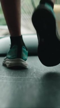 Spor salonundaki koşu bandında koşan bir adamın spor ayakkabılarını kapatın.