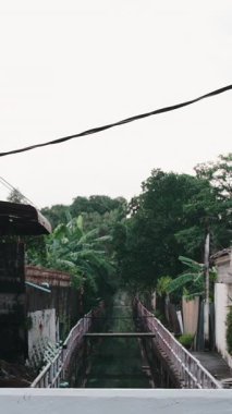 Geleneksel bir Tayland köyünde, bir kanalın üzerinde yürüyen Asyalı genç bir çift.