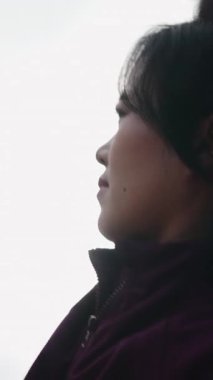 Sakin bir Taylandlı kadının sabah yogası sırasında kolunu yukarı doğru açtığı düşük açılı bir çekim.