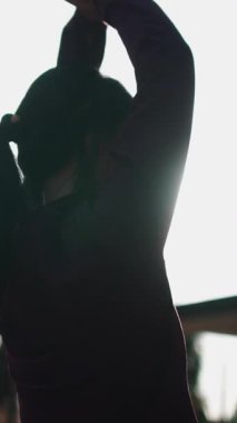 Güzel bir kadın sabahın köründe dışarıda lens ışığında yoga yapıyor.