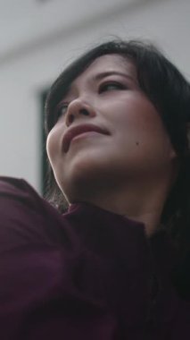 Spor giyim içindeki sakin Asyalı kadın yoga seansından sonra dinleniyor ve parlak güneş ışığının tadını çıkarıyor.