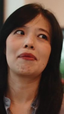 Neşeli Asyalı kadın içeride arkadaşlarıyla konuşurken mutlu bir şekilde sohbet ediyor ve duygularını ifade ediyor.