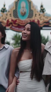 Bir grup mutlu Asyalı arkadaş dışarıda dolaşırken konuşuyor ve gülüyorlar, FullHD dikey