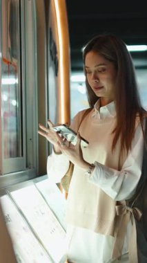 Arkadaşlarıyla gülümseyen genç bir kadın dijital menüden sipariş vermek için self servis makinesi kullanıyor.