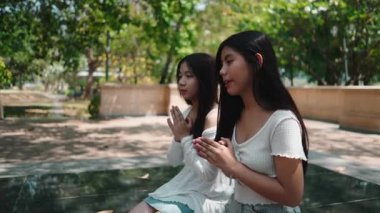 İki inançlı genç kadın huzur dolu bir parkta otururken birlikte dua ediyorlar.