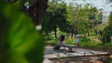 İki güzel bayan arkadaş birlikte vakit geçiriyorlar. Güzel yeşil bir parkta sohbet ediyorlar.