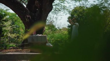 İki genç Güneydoğu Asyalı kadın bir yaz parkında takılıyor ve eğleniyorlar.