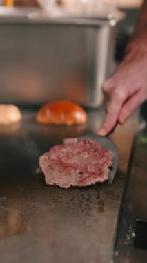 Erkek aşçı, profesyonel bir restoran mutfağında hamburgerler için taze et köftesi pişiriyor.