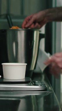 Profesyonel aşçı, ticari bir mutfakta yemek hazırlıyor ve tartılıyor.