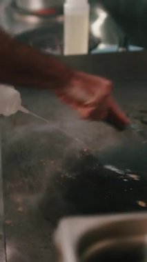 Tanımlanamayan şef vardiyanın sonunda sıcak paslanmaz çelik bir ızgarayı temizliyor.