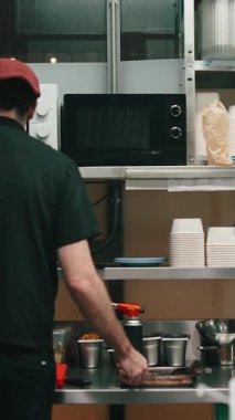 Meşgul bir restoranda servis siparişi için yemek hazırlayan profesyonel bir şef.