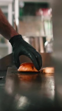 Bir restoranın mutfağında ızgara taze brioche burger ekmeği pişiren bir aşçıya yaklaş.