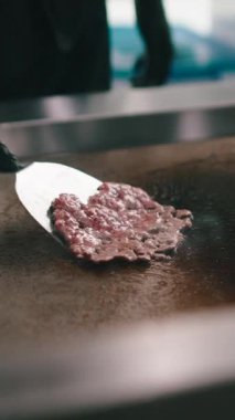 Siyah eldivenli bir şef, mutfakta ızgara ızgara ızgara et köftesi pişiriyor.