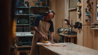 Marangozluk işinde yetenekli bir marangozdu. El yapımı bir gitar gövdesini dikkatlice zımparalıyordu.