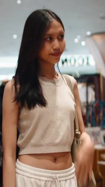 Bir alışveriş merkezindeki giyim mağazasında gülümseyen ve gezinen güzel bir transseksüel kadın.