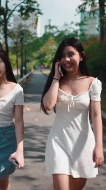 Biri cep telefonuyla konuşurken, iki genç arkadaş şehir parkında yürüyorlar.