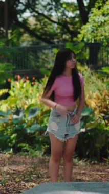 Uzun saçlı mutlu genç kız dans ediyor ve gündüz vakti yeşil bir bahçede eğleniyor.