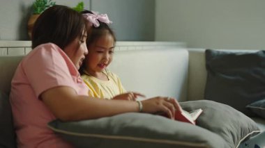 Anne, genç kızıyla masal kitabı okuyor, sevgi dolu aile anını paylaşıyor.