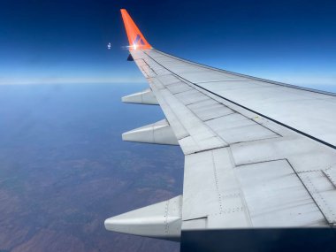 Bulutların üzerinde uçan bir uçağın kanadı ve mavi gökyüzü