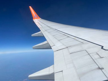 Bulutların üzerinde uçan bir uçağın kanadı. Gökyüzü bulutların arasında uçuyor.