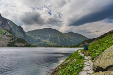 Yaz mevsiminde Polonya Lisesi Tatras 'ta dağ göllerinin yakınında yürüyen bir turist kızla..