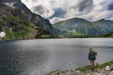 Yaz mevsiminde Polonya Lisesi Tatras 'ta dağ göllerinin yakınında yürüyen bir turist kızla..