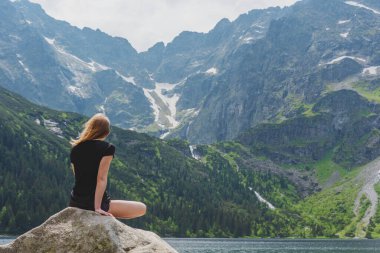 Yaz mevsiminde Polonya Lisesi Tatras 'ta dağ göllerinin yakınında yürüyen bir turist kızla..