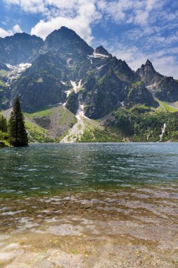Yaz mevsiminde Polonya Lisesi Tatras 'ta dağ göllerinin yakınında yürüyen bir turist kızla..