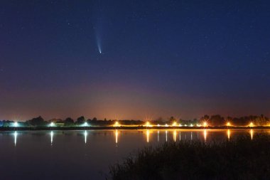 Samanyolu 'nun yanındaki nehirde büyülü bir yıldızlı gece ve gökyüzünde bir kuyruklu yıldız.