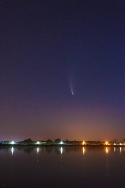 Samanyolu 'nun yanındaki nehirde büyülü bir yıldızlı gece ve gökyüzünde bir kuyruklu yıldız.