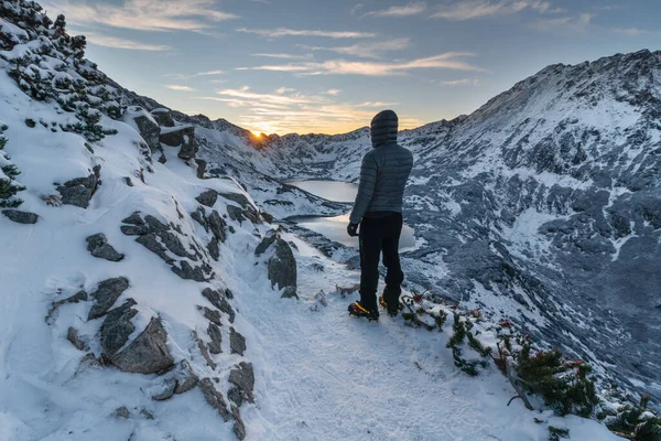 Bir turist kar kaplı Tatras 'ta gün batımını izliyor