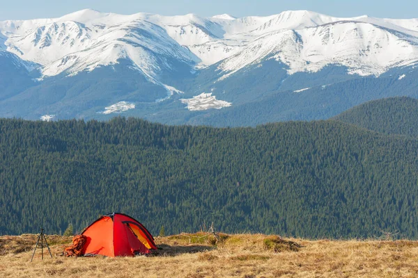 春天降临在乌克兰喀尔巴阡山脉的山谷里 在一个红色旅游帐篷的背景下俯瞰着覆盖着雾的雪峰 免版税图库图片