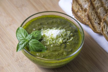 Taze Fesleğenli yeşil pesto küçük cam kapta ahşap arka plan üzerinde bırakır.