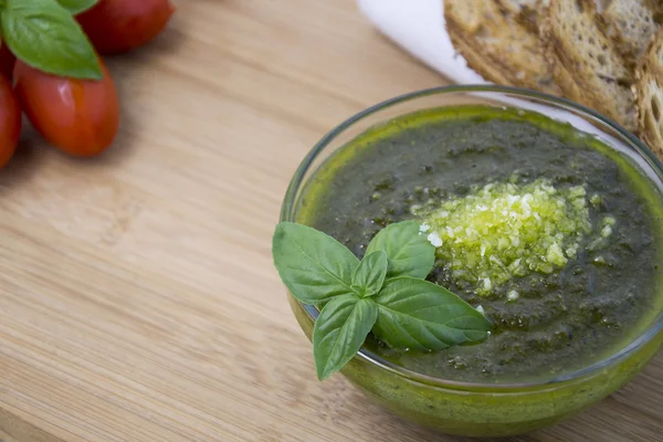 Pesto verde con foglie di basilico fresco in piccola ciotola di vetro su fondo di legno — Foto Stock